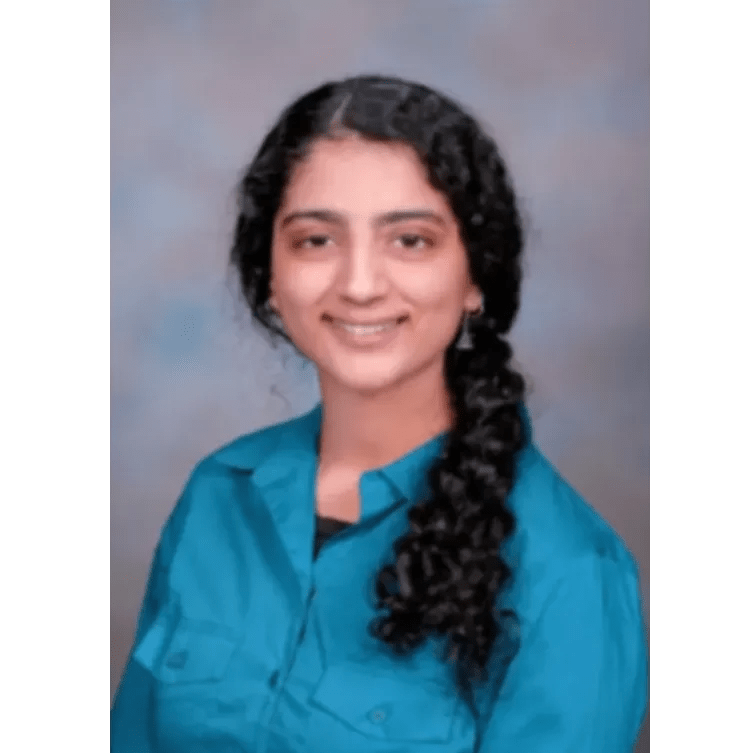 Image of a female dentist with black hair in a braid, facing the camera and smiling 